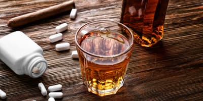 Pills and a glass of alcohol on a table